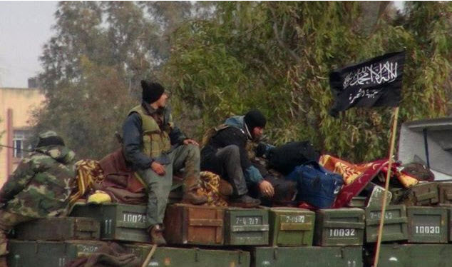 al-Qaida affiliated Jabhat al-Nusra sit on a truck full of ammunition at Taftanaz air base