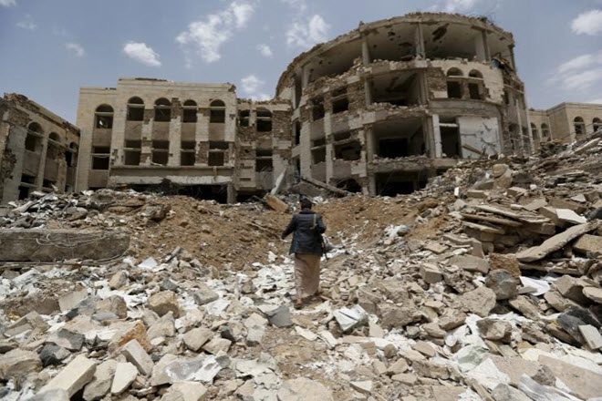 أحد قوات الدفاع الشعبي اليمني يمشي أمام المجمع الحكومي التي دمرتها الغارات الجوية السعودية في الآونة الأخيرة، في اليمن