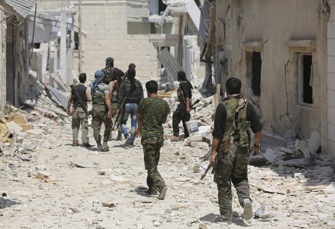 مقاتلون مسلحون يحملون أسلحتهم وهم يسيرون نحو مواقعهم في بلدة موورك في محافظة حماة. - الصورة لرويترز 