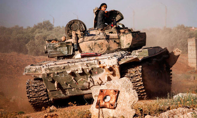 مقاتل سوري يركب دبابة بالقرب من خط المواجهة ضد القوات الحكومية غرب مدينة درعا الجنوبية يوم الثلاثاء. (ا ف ب)