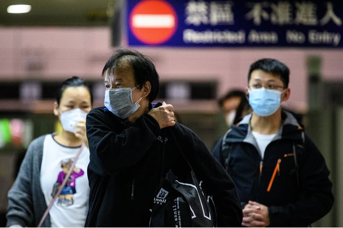 راكب يرتدي قناع الوجه للحماية عند وصوله من شنتشن إلى هونغ كونغ في محطة لو وو إم تي آر